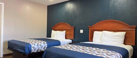 Two beds with wooden headboards, a dark wall, and a wooden floor.