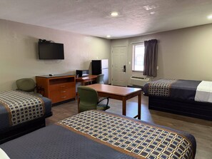 Une chambre d’hôtel avec deux lits, un bureau, une chaise, une télévision et une porte.
