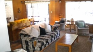 A living room with a patterned sofa, a coffee table, and a dining area with chairs and a table. - 842 Cirugu (South Lake Tahoe)