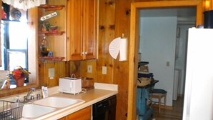 A kitchen with wooden cabinets, a white countertop, a sink, a toaster, and a refrigerator. - 3663 Forest Ave (South Lake Tahoe)