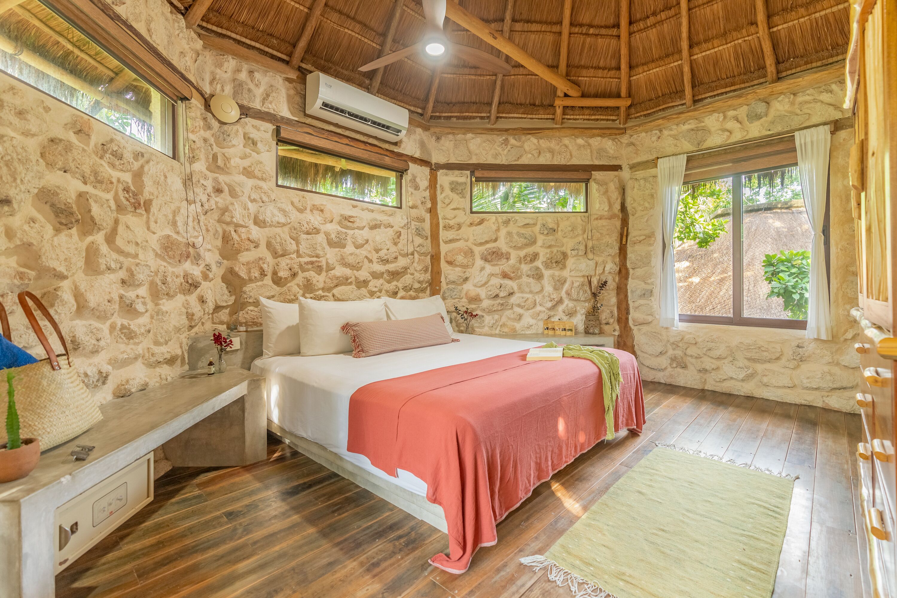 A stone-walled bedroom with a bed, a bench, and a window.