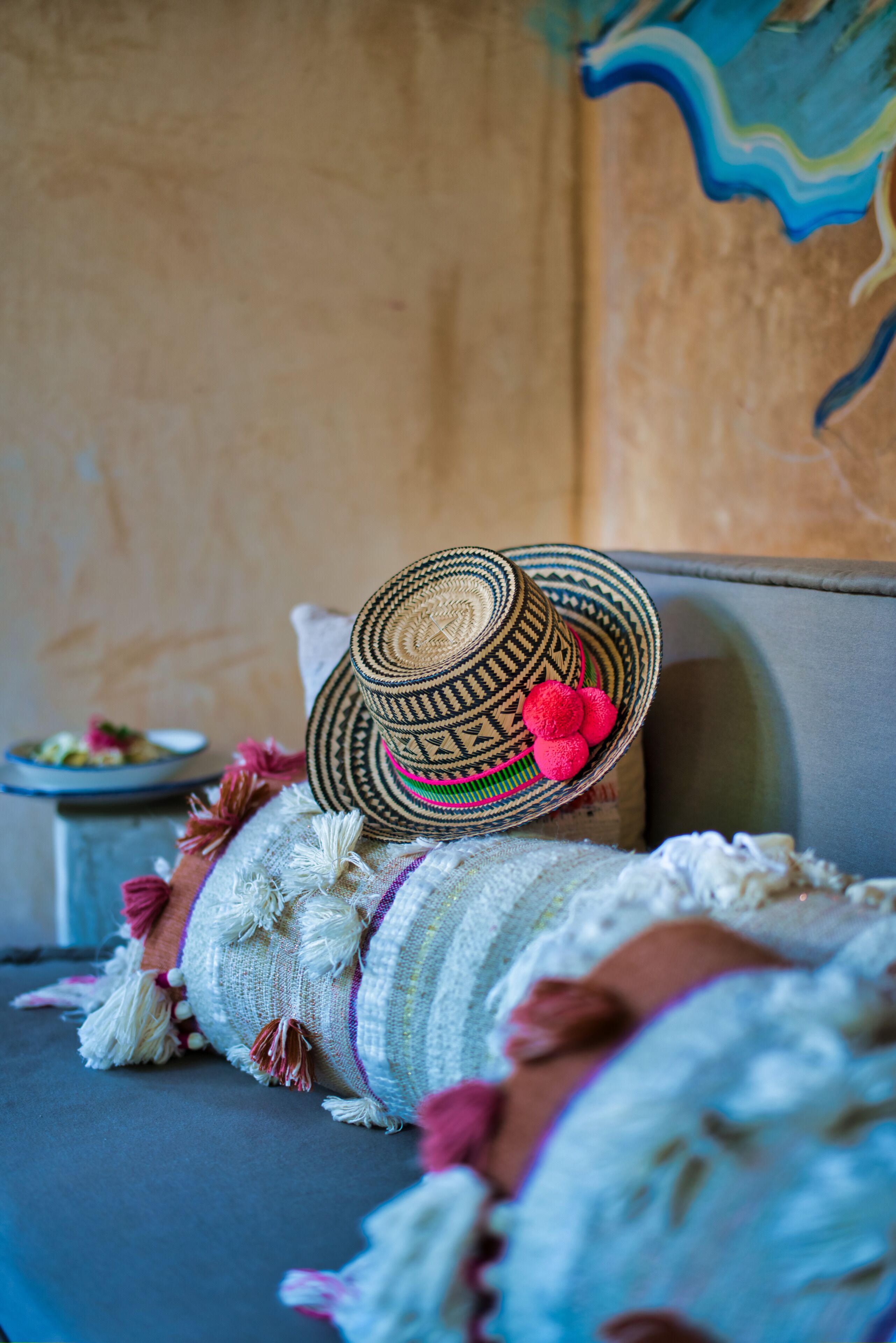 A woven hat with a decorative band and tassels on a cushioned surface.