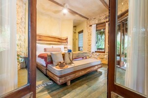Un dormitorio acogedor con pared de piedra, una cama de madera y un sofá cama.