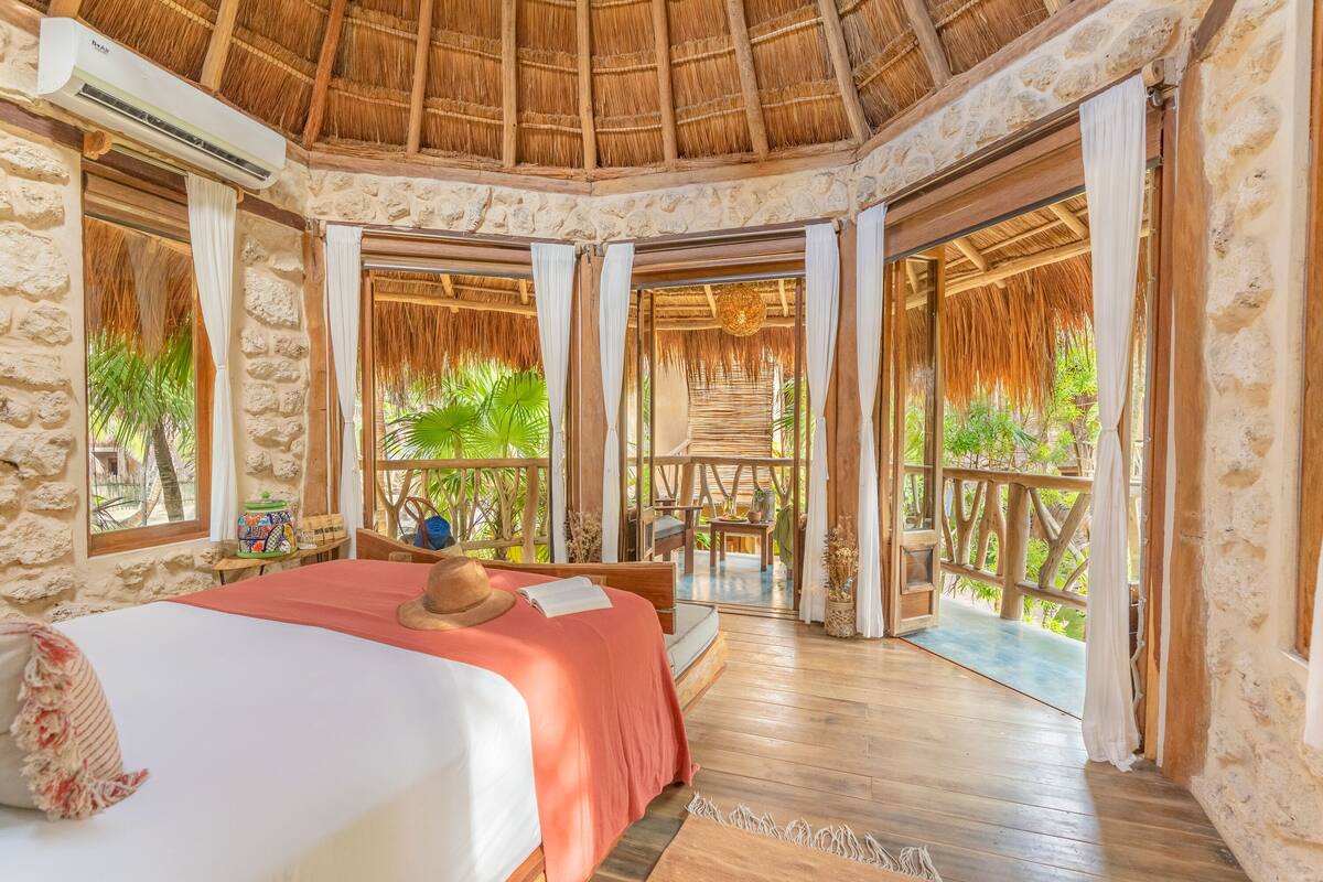 Una habitación con cama, un sombrero y una ventana.