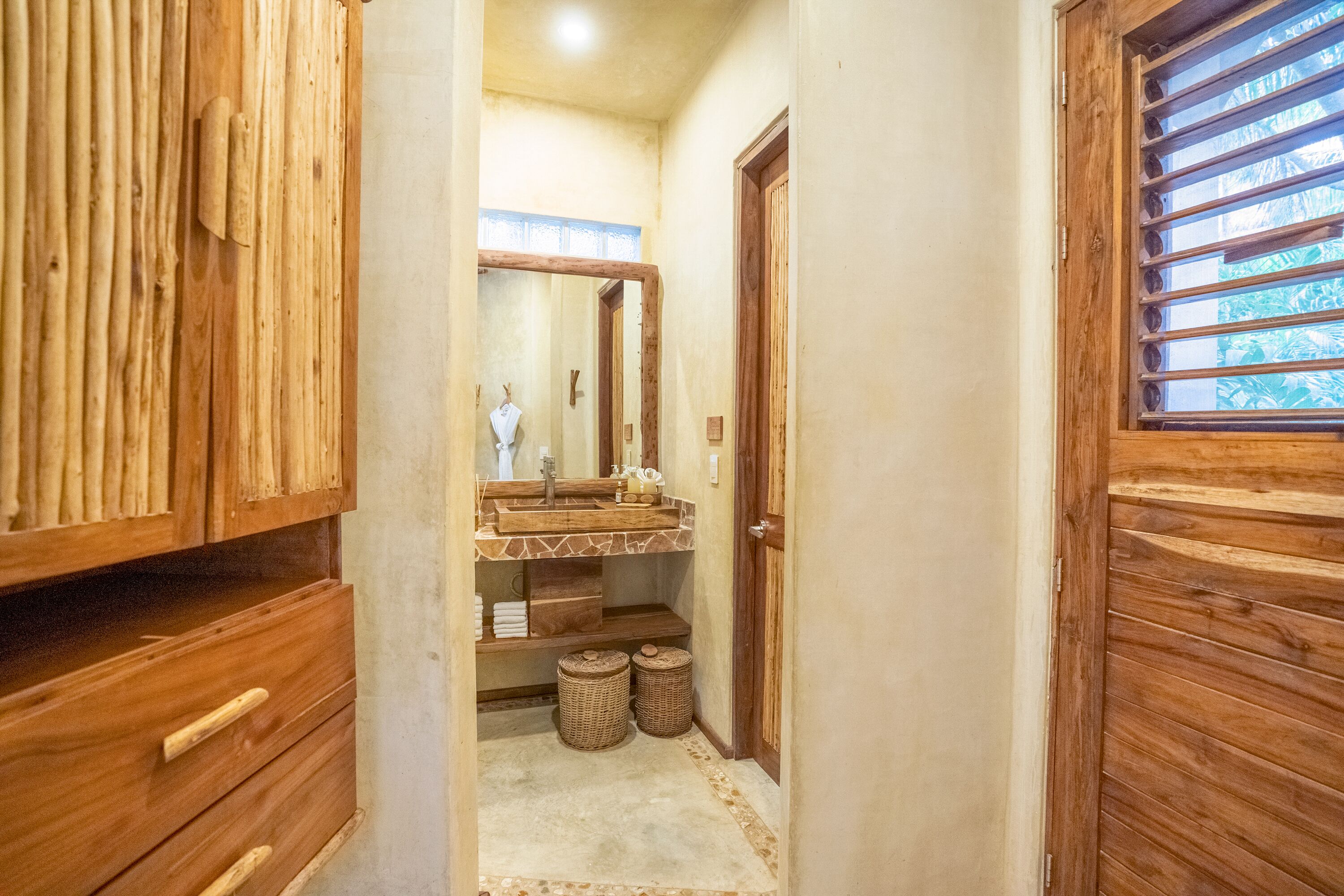 A wooden bathroom with a wooden vanity, a mirror, and a window with horizontal bars.