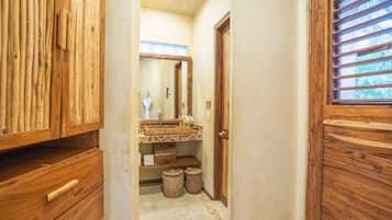 A wooden bathroom with a wooden vanity, a mirror, and a window with horizontal bars.