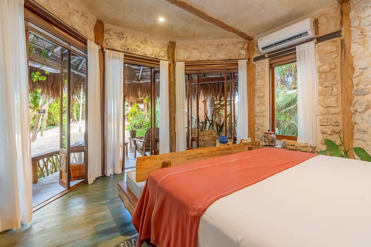 Una habitación con cama, vigas de madera, paredes de piedra y vistas al exterior.