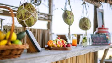 A wooden bar with a fruit display, hanging decorations, and a chalkboard menu.