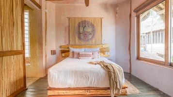 Une chambre à coucher avec un lit en bois, une grande fenêtre et une tapisserie suspendue au mur.