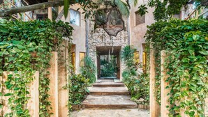 A stone pathway leading to a doorway, surrounded by lush greenery and wooden structures. - Alaya Tulum (Tulum)