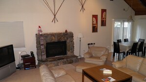 A living room with a stone fireplace, leather sofas, a coffee table, and a television. - 2728 Springwood Dr. (South Lake Tahoe)