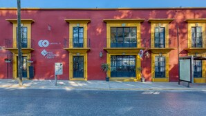 Un hotel con fachada roja, detalles amarillos y ventanas negras. Tiene un cartel que indica que es un hotel y el número 526.