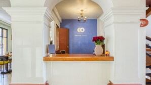 Una zona de recepción con pared azul, una araña, un mostrador de madera y un letrero que dice "Capital O Parador Cerezo".