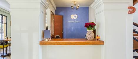 Una zona de recepción con pared azul, una araña, un mostrador de madera y un letrero que dice "Capital O Parador Cerezo".