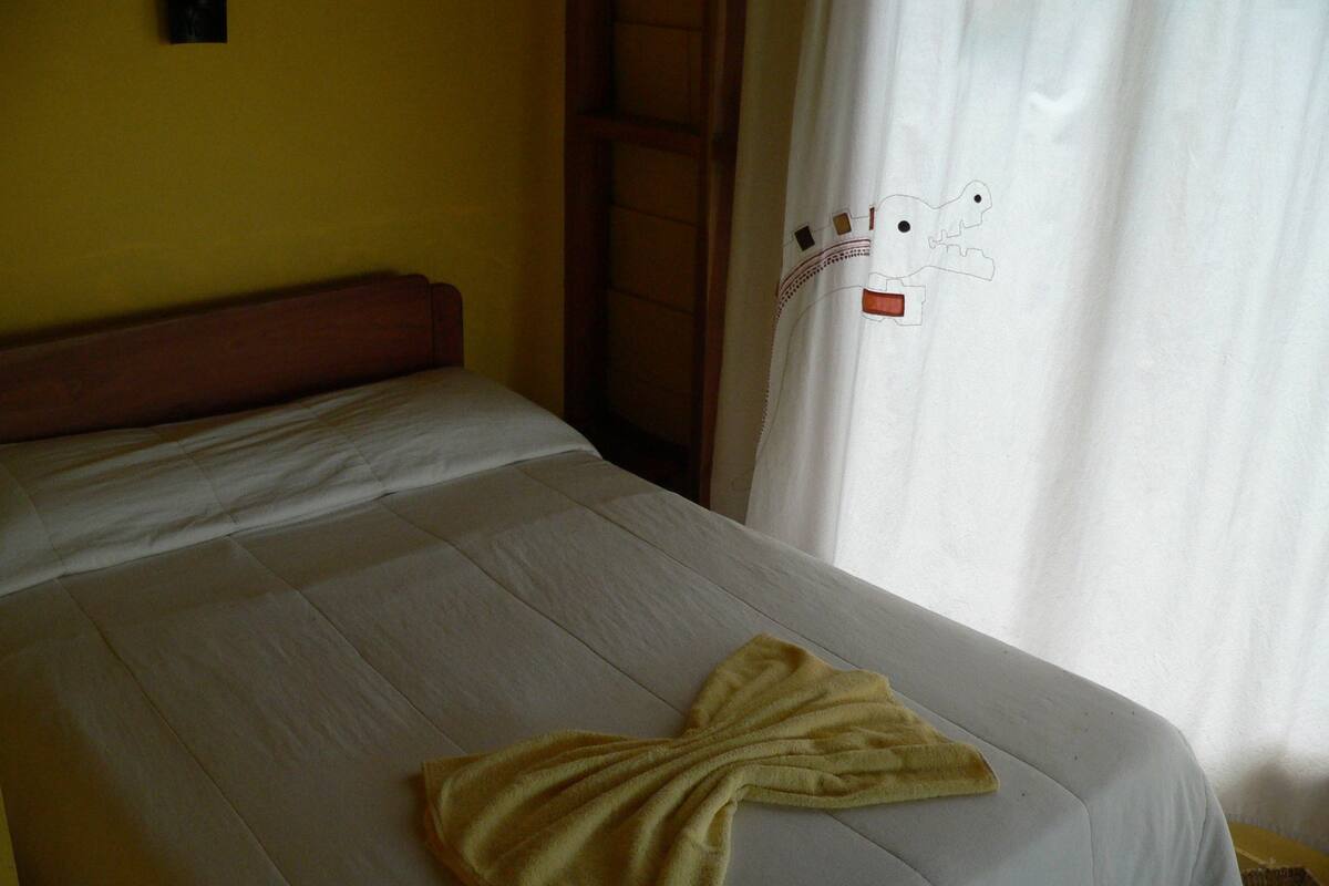 A bed with a white bedspread and a towel folded in the shape of a bow.