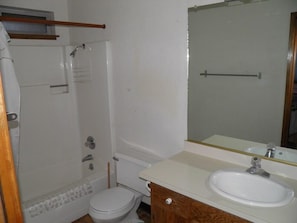 A bathroom with a toilet, sink, and shower area.