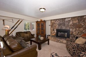 A living room with leather sofas, a stone fireplace, and a wooden cabinet. - 2853 Springwood Dr. (South Lake Tahoe)