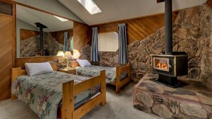 A cozy room with two wooden beds, a stone fireplace, and a skylight. - 3042 Sierra Blvd. (South Lake Tahoe)