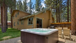 A two-story wooden cabin with a hot tub in the backyard, surrounded by tall trees. - 3042 Sierra Blvd. (South Lake Tahoe)