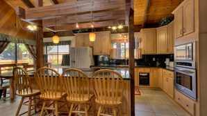 A kitchen with wooden cabinets, a central island with chairs, and modern appliances. - 3042 Sierra Blvd. (South Lake Tahoe)
