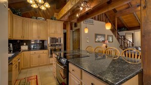A kitchen with wooden cabinets, granite countertops, a built-in oven, and a dining area with chairs. - 3042 Sierra Blvd. (South Lake Tahoe)