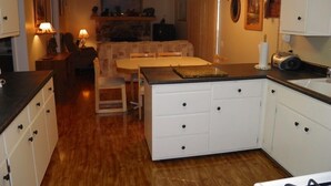 Una cocina compacta con armarios blancos, una isla central y un comedor con mesa y sillas.