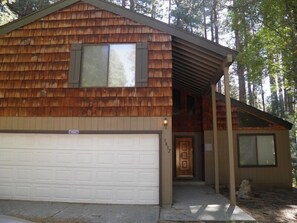 A wooden cabin with a garage, a front door, and a covered porch area. - 3832 Regina Rd. (South Lake Tahoe)