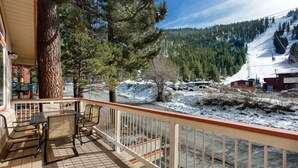A wooden deck with a table and chairs, overlooking a snowy landscape with trees and a mountain in the background. - 3851 Saddle Road (South Lake Tahoe)