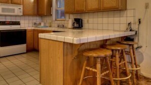 A kitchen with wooden cabinets, a white countertop, and a central island with stools. - 3851 Saddle Road (South Lake Tahoe)