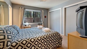 A bedroom with a bed, a television, a window with curtains, and a bedside table with a lamp. - 3221 Marlette Circle (South Lake Tahoe)