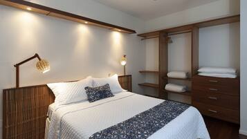 A bedroom with a bed, bedside lamps, a wardrobe, and a ceiling fan.