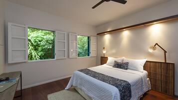 A bedroom with a bed, a desk, and two windows with shutters.