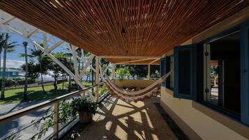 Un'amaca sotto un soffitto in legno, un balcone con ringhiera e vista sul mare.