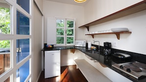 Una cocina moderna con microondas incorporado, cafetera y un lavamanos. Se ve un ventanal con vistas a la vegetación.