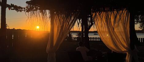A sunset view from a covered outdoor area with a view of the water.