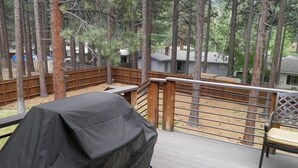 A covered grill on a wooden deck with a view of a forested area and a house in the background. - 3354 Red Lake Rd (South Lake Tahoe)