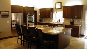 A modern kitchen with dark wood cabinets, stainless steel appliances, and a large island with bar stools. - 3354 Red Lake Rd (South Lake Tahoe)