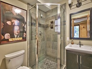 A bathroom with a glass-enclosed shower, a toilet, and a sink with a mirror above it. - 3877 Crest Drive (South Lake Tahoe)