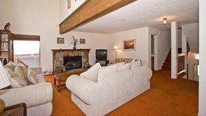Een woonkamer met een open haard, een zithoek en een televisie.