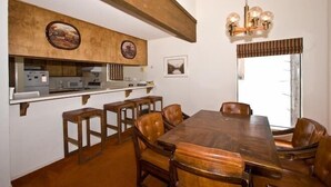 A dining area with a wooden table and chairs, a chandelier, and artwork on the walls.