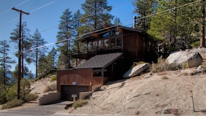 Une cabane moderne à deux étages, avec une façade en bois, un garage et un escalier menant à l’étage supérieur.