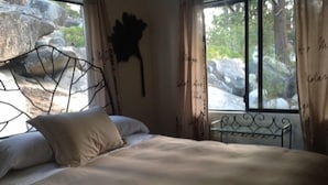Un lit avec une tête de lit en métal, une table de chevet et une fenêtre avec des rideaux.