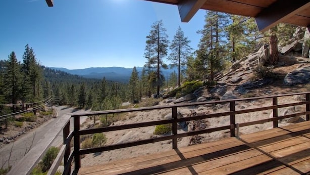 Une terrasse en bois offrant une vue sur un paysage montagneux.