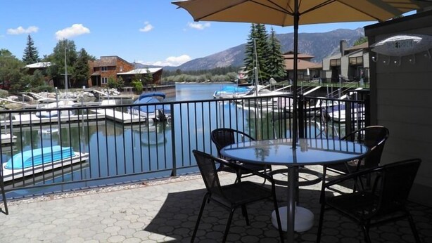A balcony with a table and chairs, overlooking a marina with boats and a swimming pool. - 357 Ala Wai Unit 205 (South Lake Tahoe)