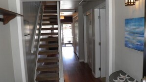 A staircase leading to a landing, a hallway with doors, and a wall-mounted light fixture. - 357 Ala Wai Unit 205 (South Lake Tahoe)