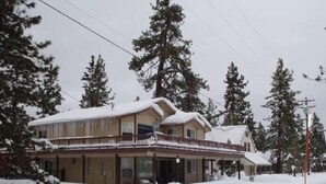 A two-story building with a balcony, surrounded by snow-covered trees.