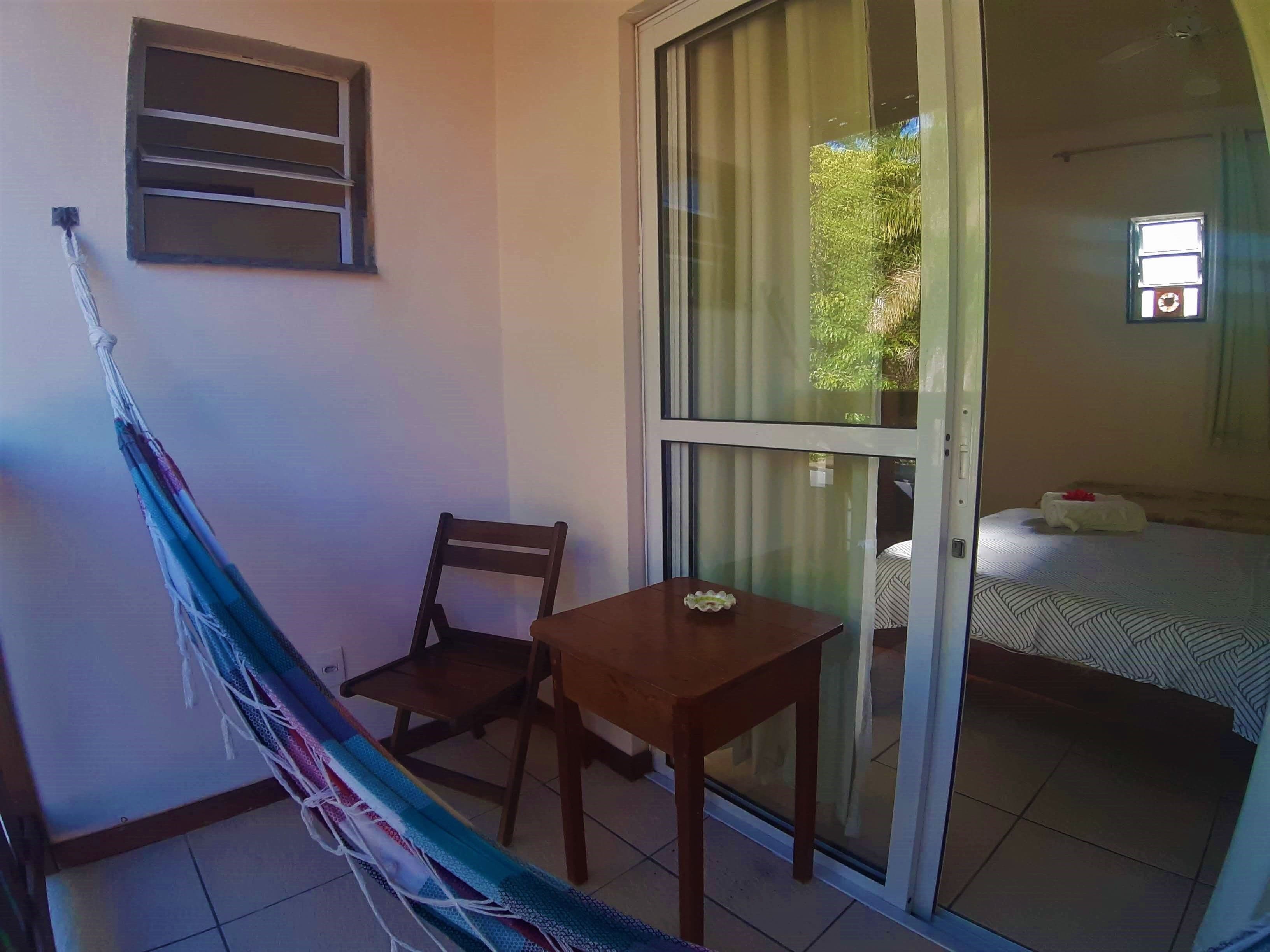 A balcony with a hammock, a wooden chair, and a small table.