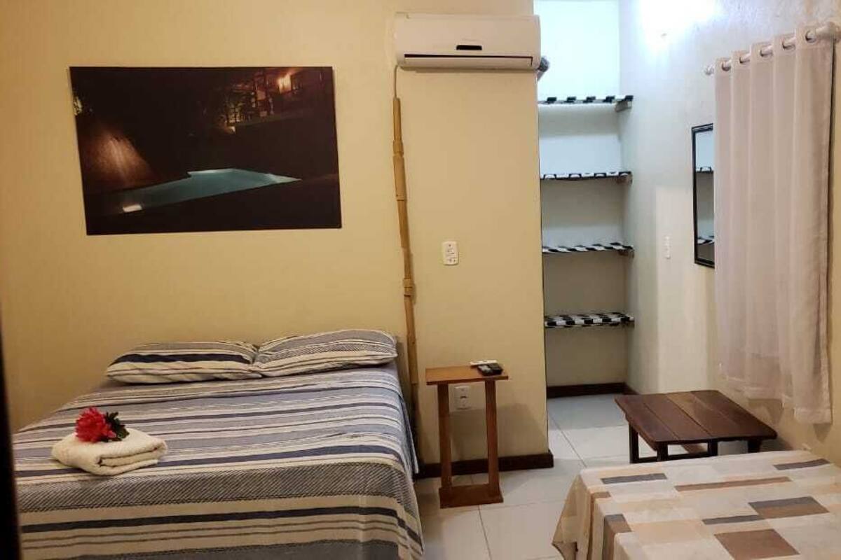 Una habitación pequeña y funcional con una cama, una mesita y una estantería.