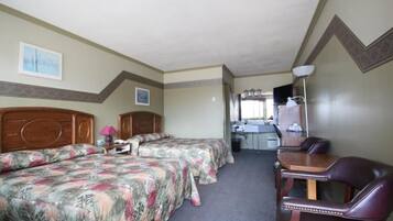 Quarto de hotel com duas camas, uma escrivaninha, uma cadeira e um banheiro ao fundo.