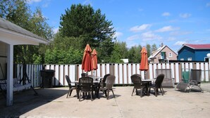 An outdoor patio with a table and chairs, surrounded by a white fence, and a blue building in the background. - Motel Marie-Dan (Sainte-Eulalie)